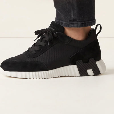 Hermès black low-top sneaker with white ridged sole and H-shaped black insert