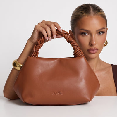 Ganni tan hobo bag with braided handle held by model