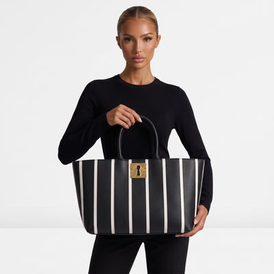 Black tote bag with vertical white stripes and gold keyhole plaque
