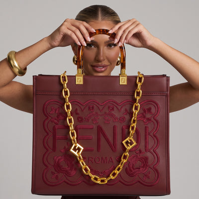 Burgundy Fendi tote bag with gold chain and tortoiseshell handles showing embossed FENDI ROMA