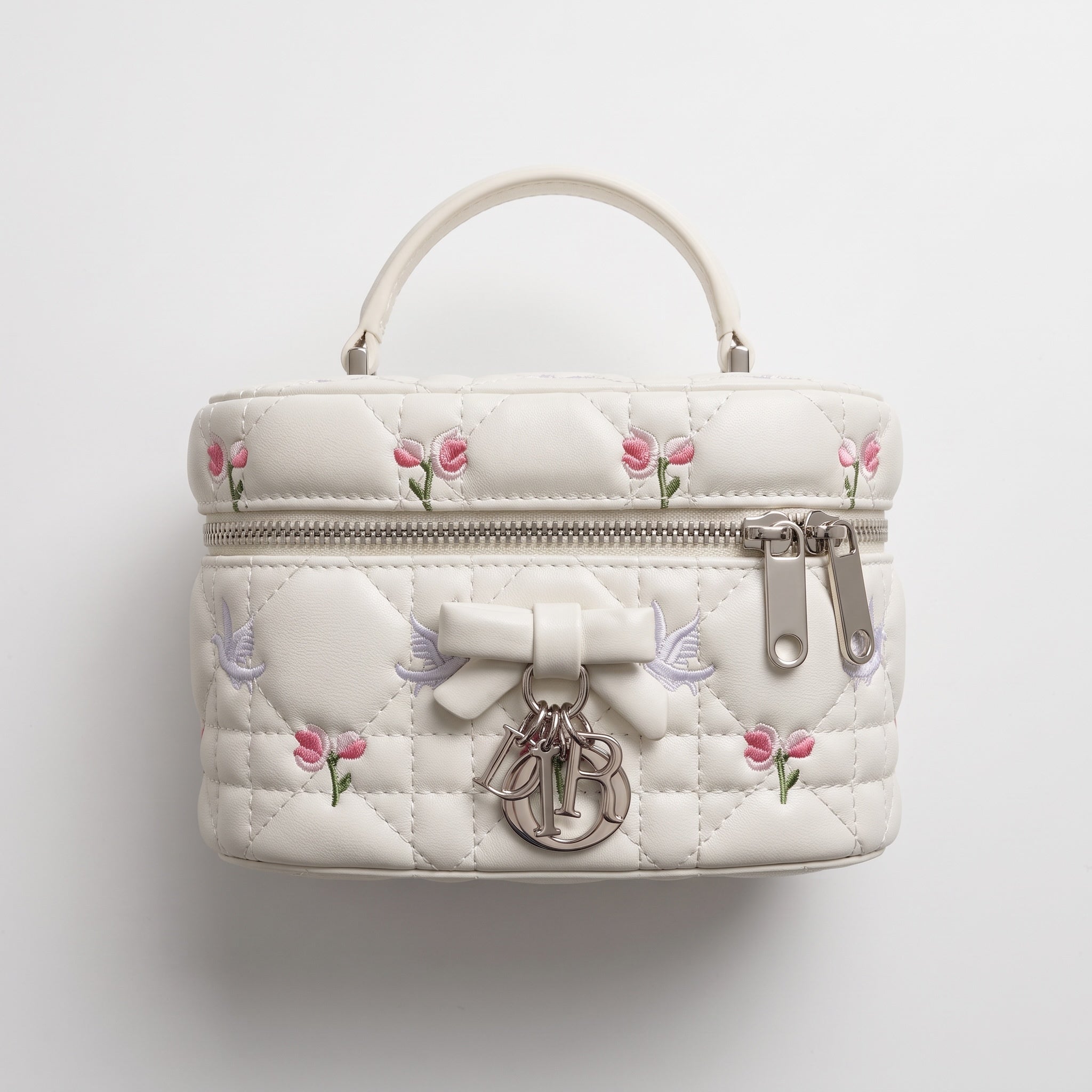 white quilted Dior vanity bag with pink floral embroidery and silver logo charms