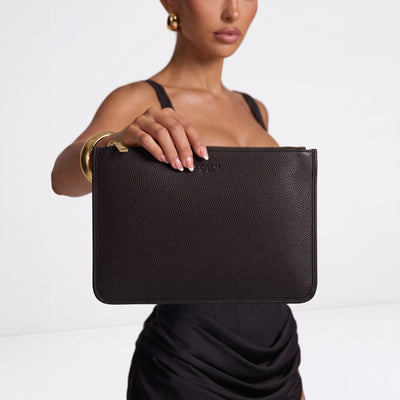 Black pebbled Coach zip pouch with gold zipper held by model