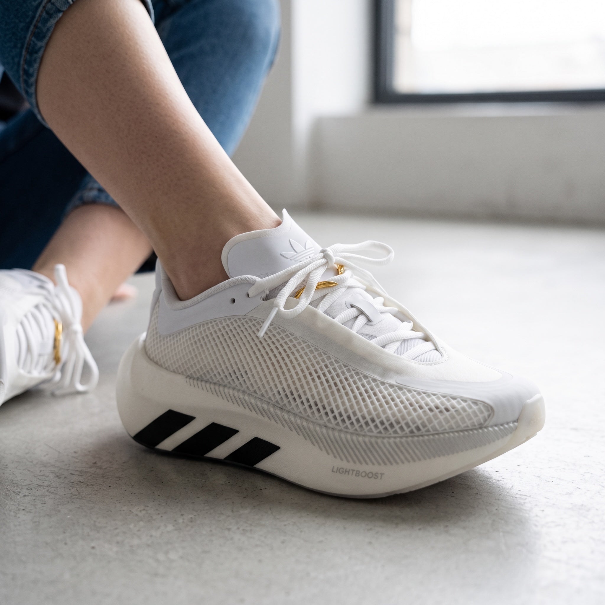 white adidas hyperboost sneaker with mesh upper and black three stripes