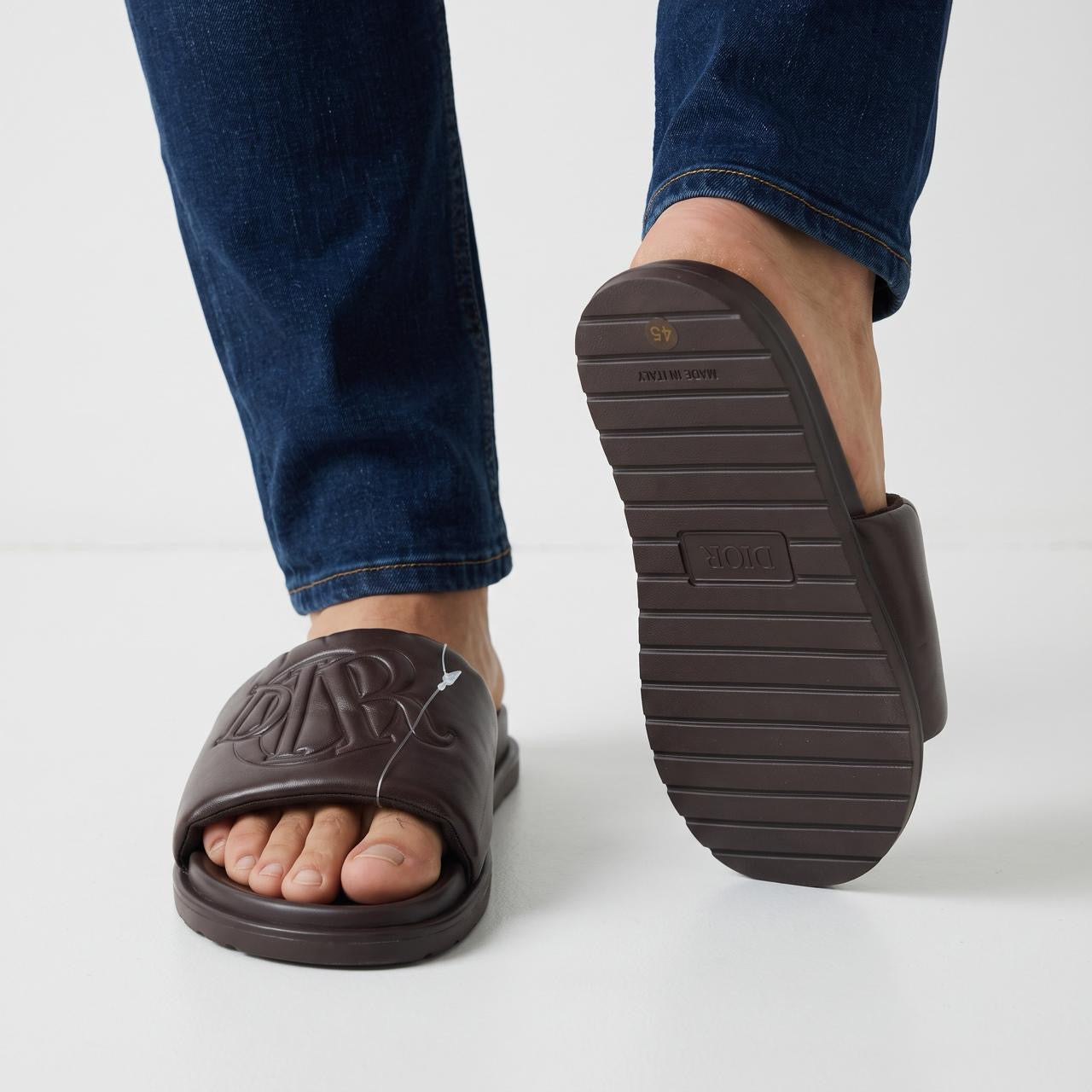 Dior dark brown padded slide sandals with embossed monogram on foot