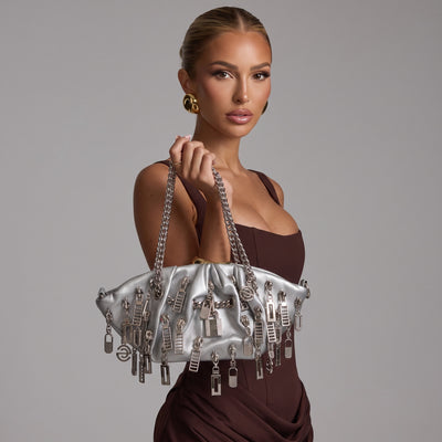 Silver metallic tote bag covered in dangling metal charms with double chain handles