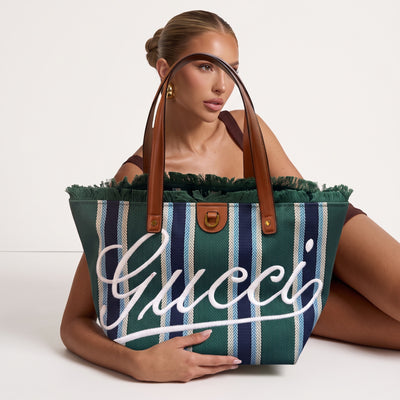 green and navy striped tote bag with brown handles and fringe