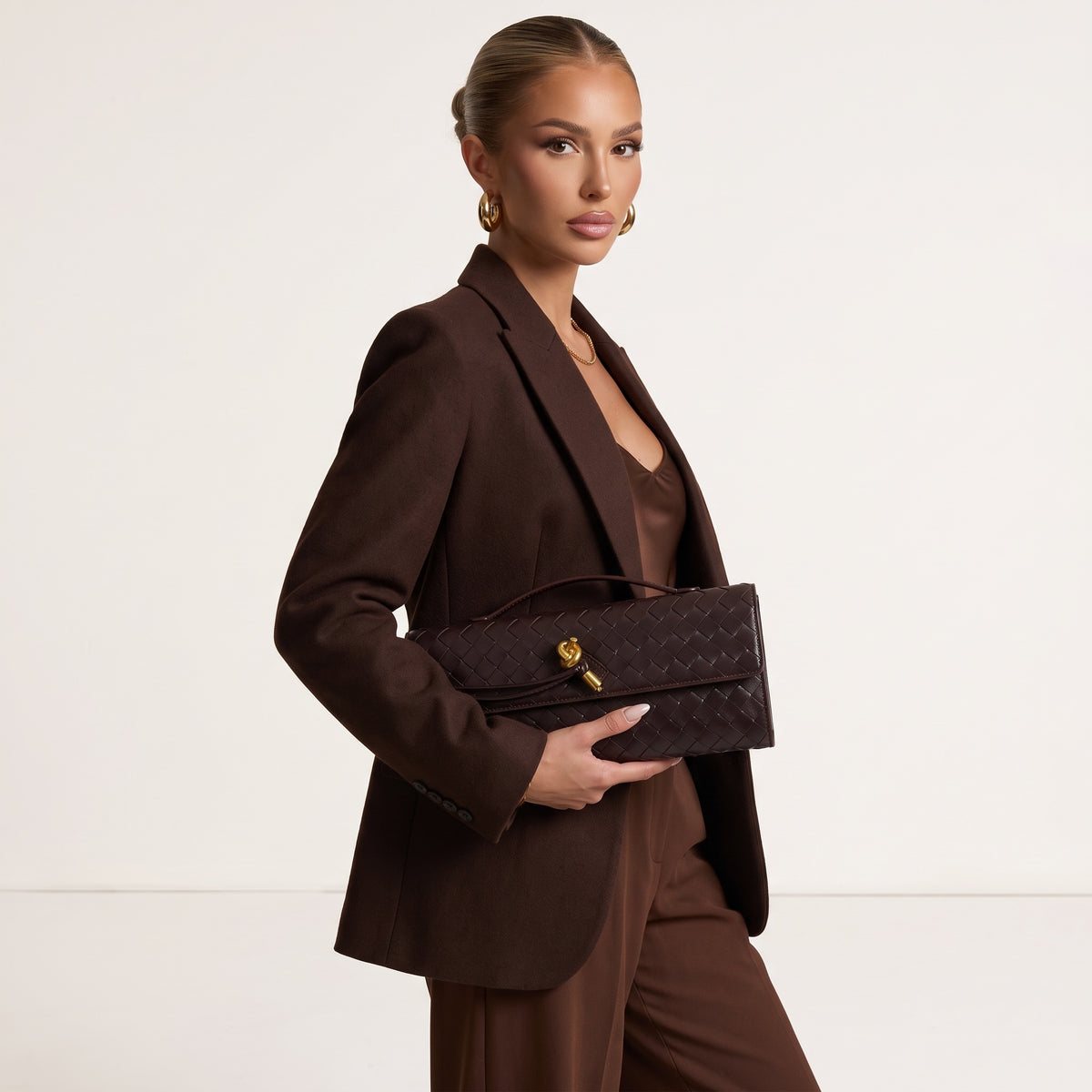 dark brown top-handle bag with interlaced pattern and gold knot clasp