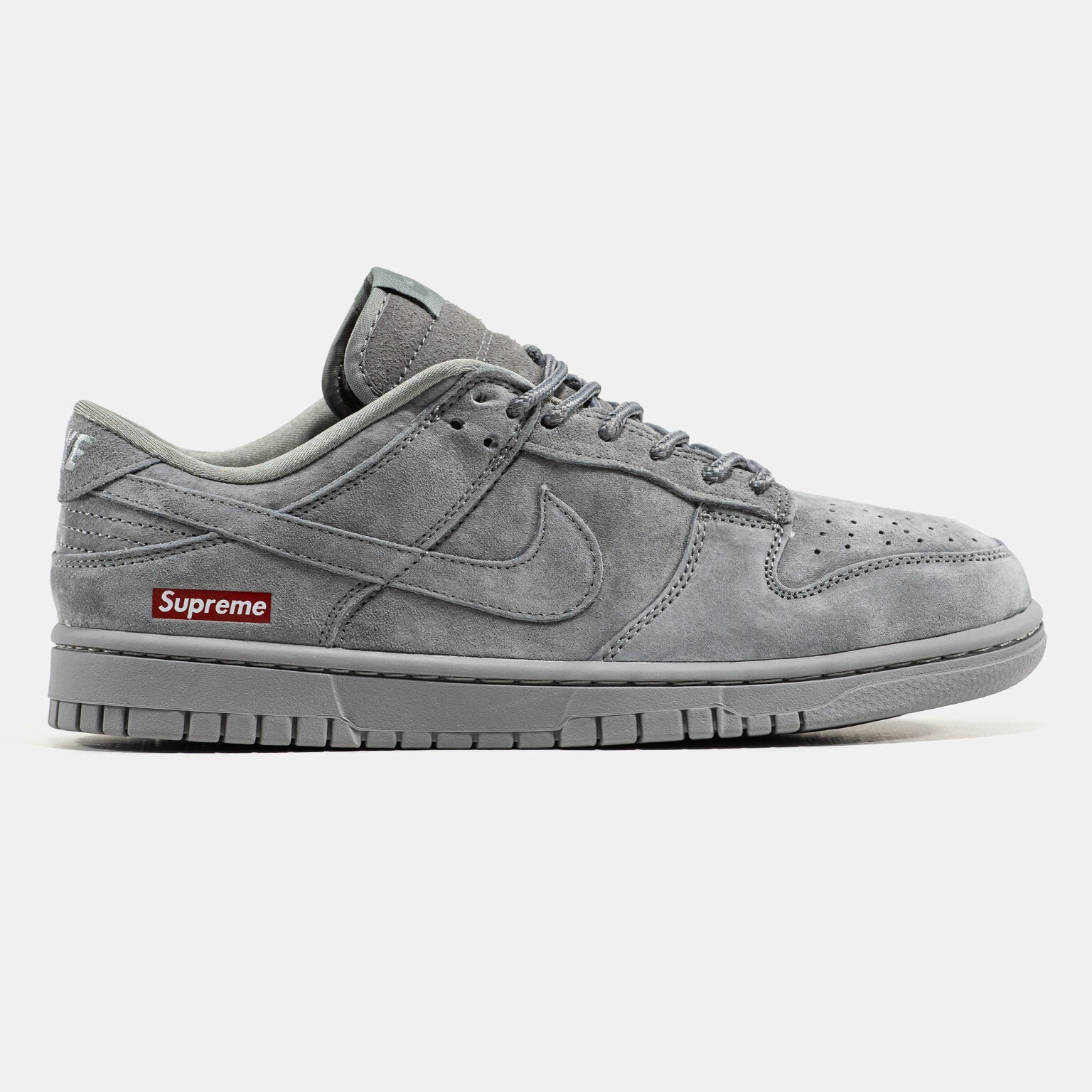 Grey Nike Dunk Low suede sneaker with small red Supreme box logo at heel