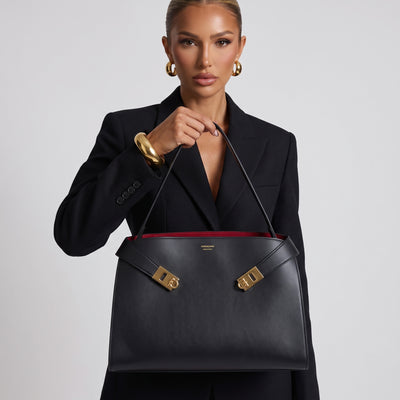 Ferragamo black structured top-handle bag with gold hardware held by model