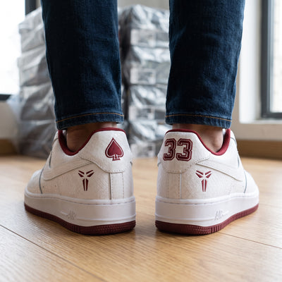 White low-top Nike Air Force 1 with burgundy accents, textured upper, Kobe logo and number 33 on heel
