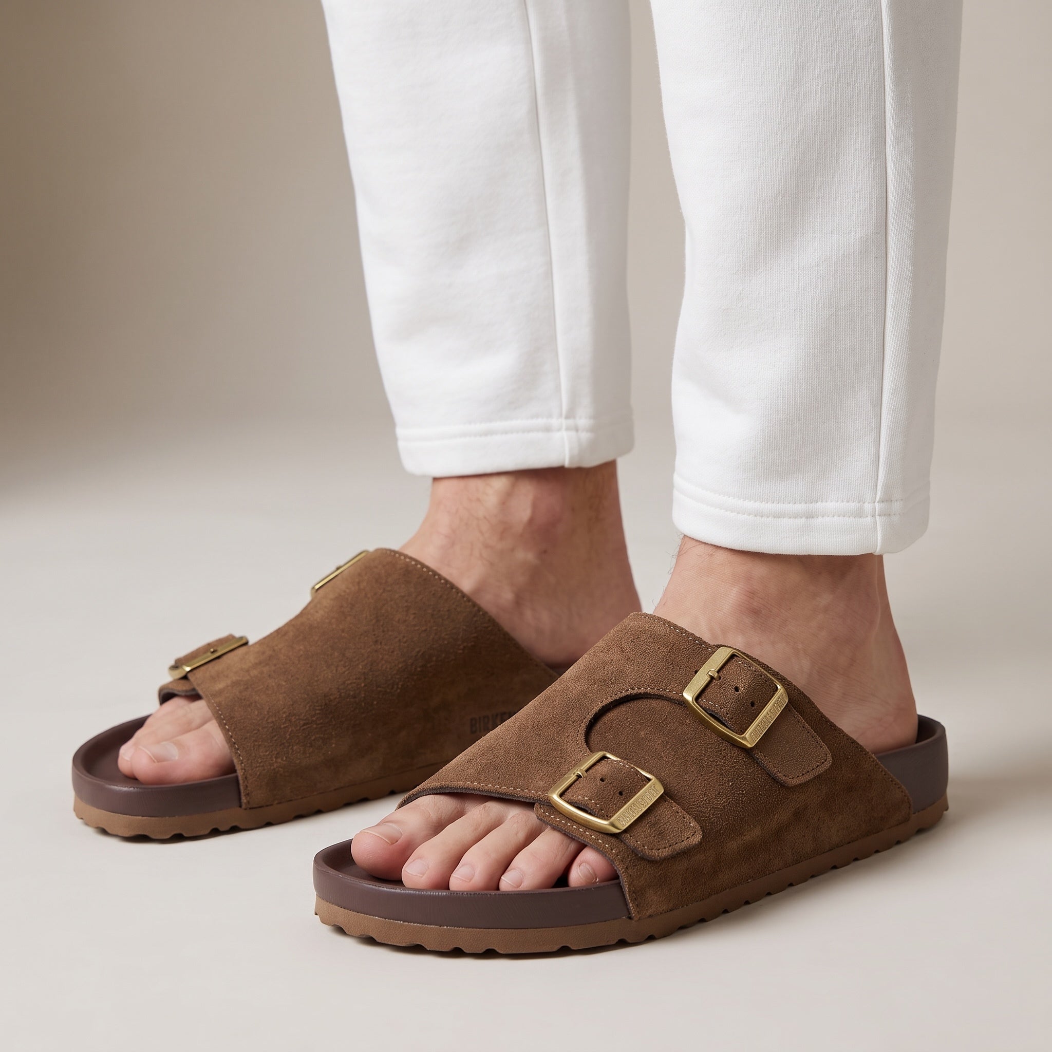 Close-up of brown suede Birkenstock Arizona sandals with double buckles on a model's feet