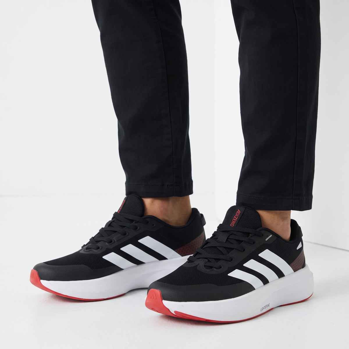 black Adidas sneakers with white stripes and red accents