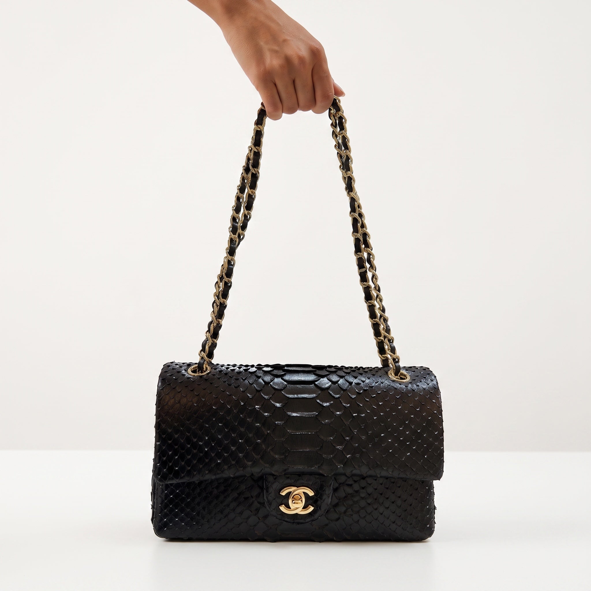 Black Chanel flap bag with scaled textured finish and gold CC turn-lock, woven gold-and-black chain strap