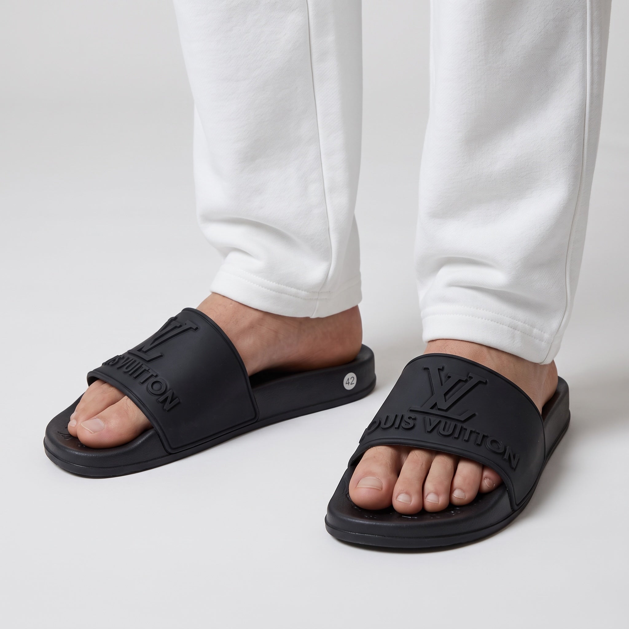 Black Louis Vuitton embossed logo slides on feet