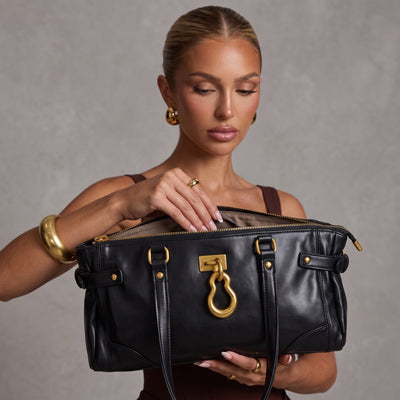 Black leather tote bag with large gold ornament and double handles