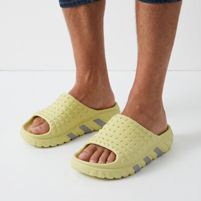 lemon yellow Adidas-style slip-on slides with textured upper and chunky treaded sole
