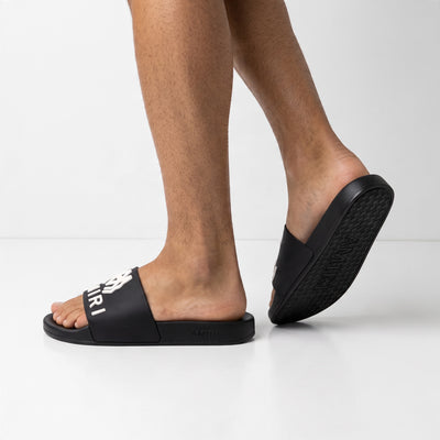 Black Amiri slide with white raised logo on strap and embossed sole