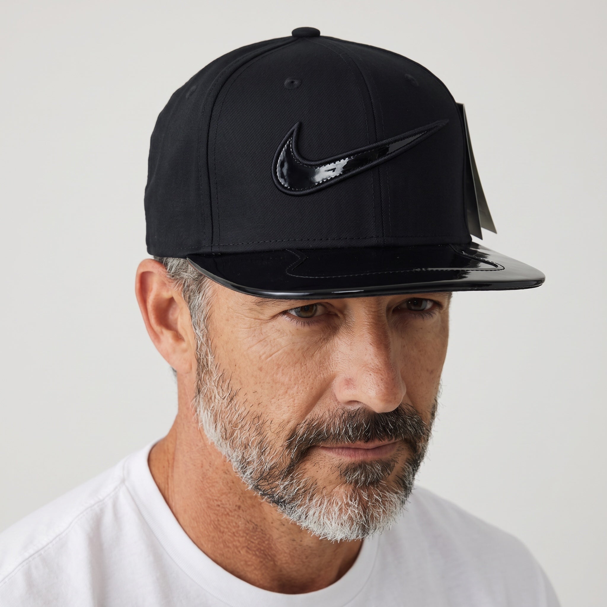 Man wearing a black Nike snapback cap with glossy patent-finish brim