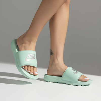 mint green Nike slides with silver logo on model's feet