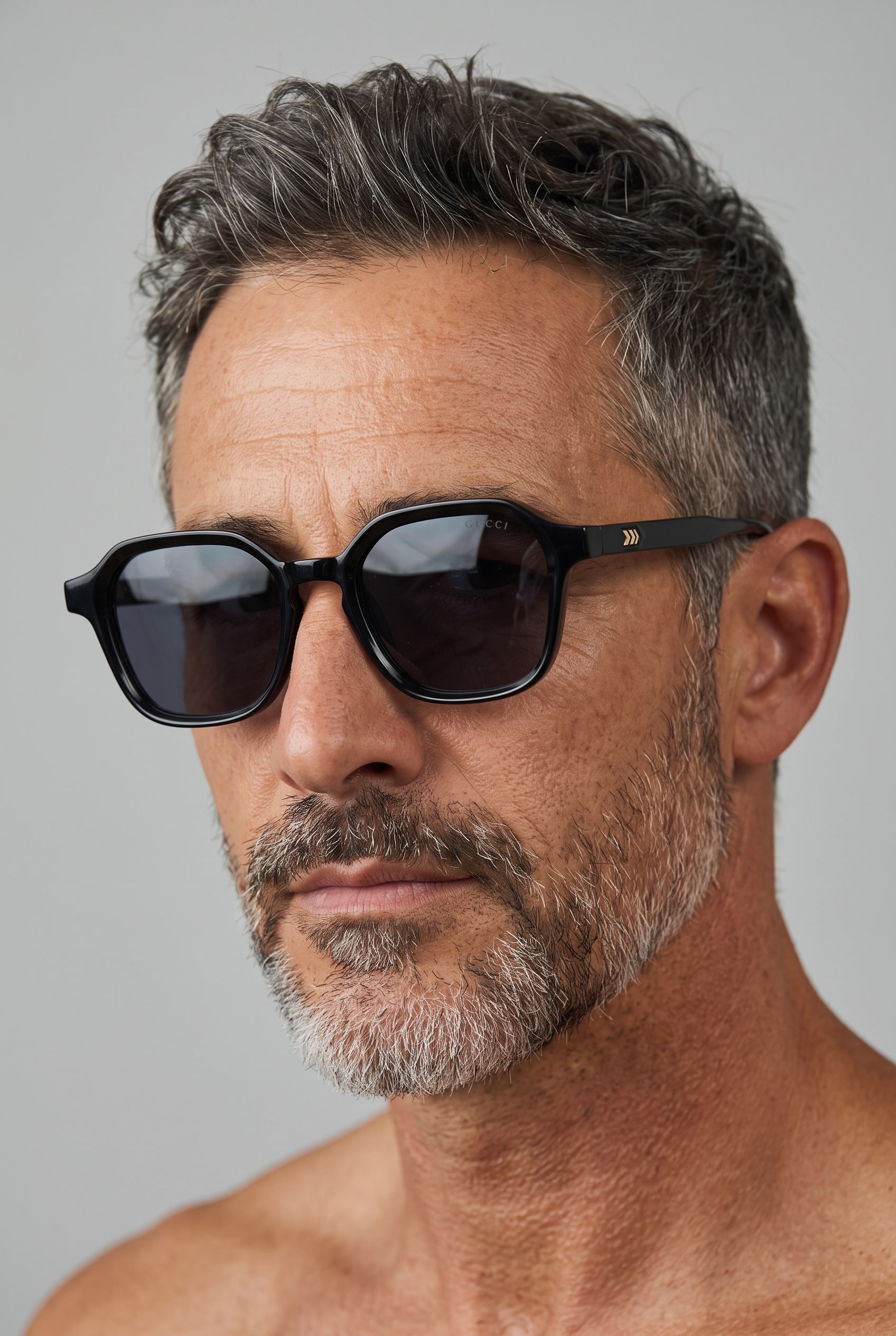 Black Gucci sunglasses with hex-shaped frame and gold temple detail on a male model