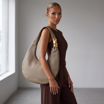 Taupe crescent hobo tote with sculptural gold hardware and pebbled texture