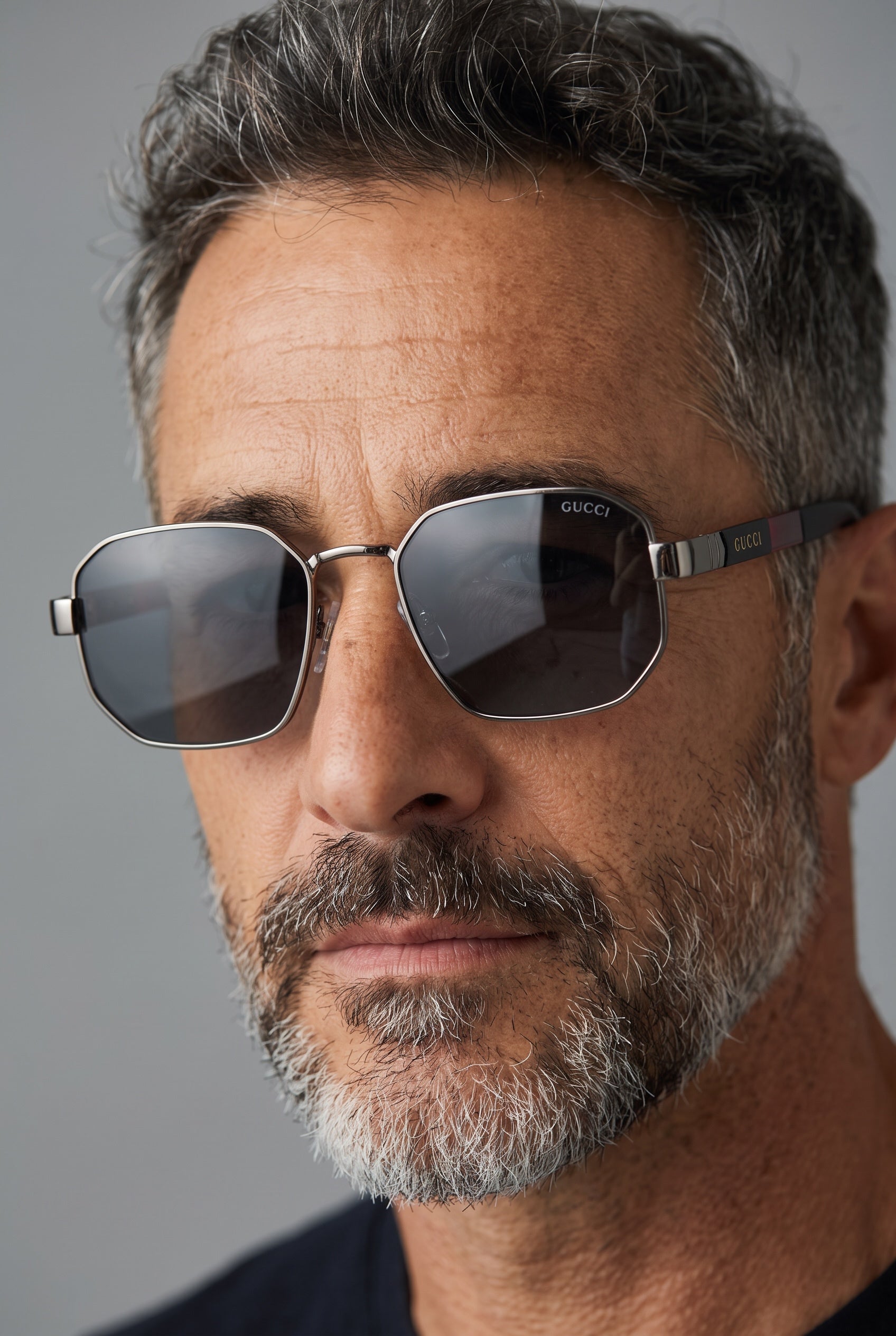 Close-up of man wearing Gucci silver hexagon sunglasses with dark lenses
