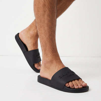 Black Balmain logo slide sandals on model feet