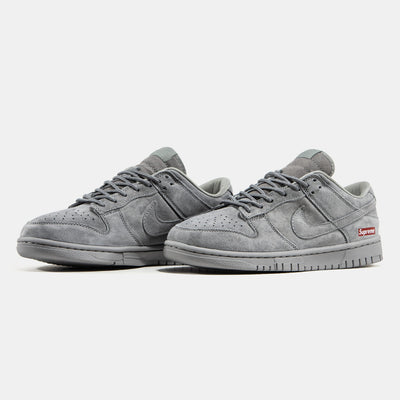Grey Nike Dunk Low suede sneaker with small red Supreme box logo at heel