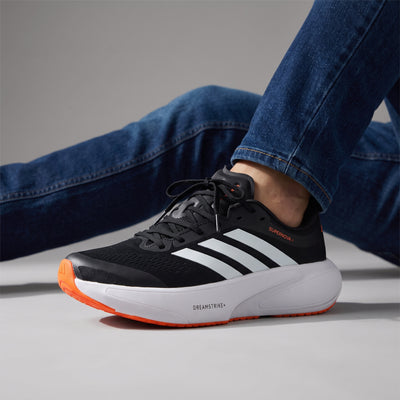 Adidas Supernova black white orange running sneaker showing Dreamstrike+ midsole and three stripes