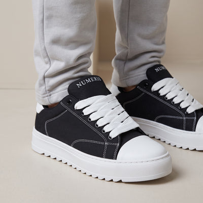 Black Numeris low-top sneakers with white laces, white toe cap and chunky ridged white sole