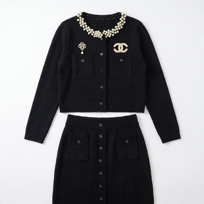 black Chanel cardigan with pearl collar and decorative brooches