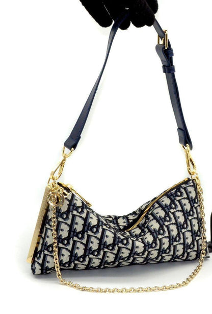 This exquisite Dior shoulder bag features the signature oblique jacquard pattern in navy and cream, a timeless symbol of the brand’s elegance. The gold-tone zipper and chain detailing add a luxurious touch, while the adjustable leather strap ensures both