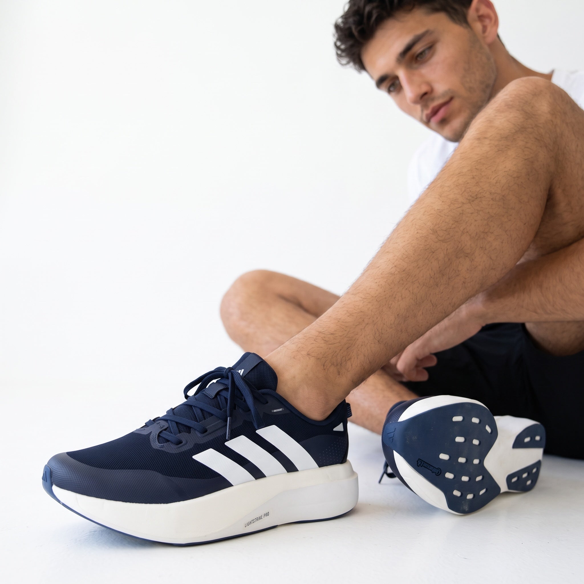 Navy and white Adidas sneakers shown on a model with chunky white sole