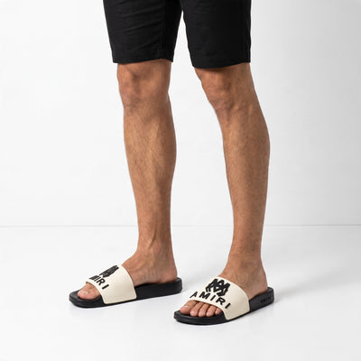 Amiri white strap black sole logo slides on model feet