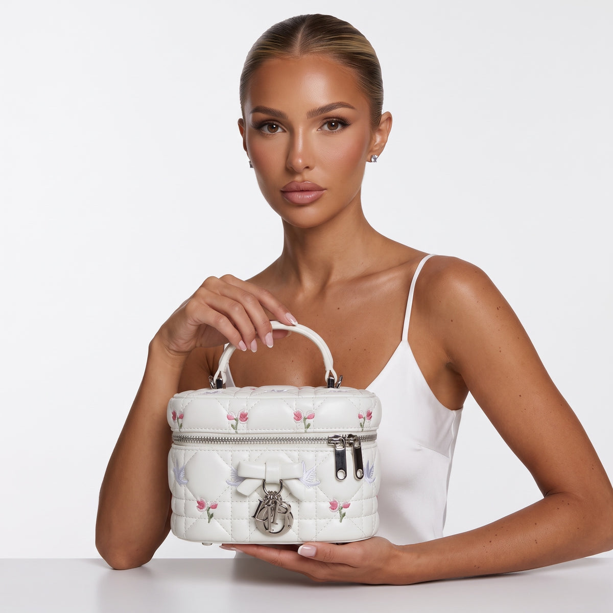 white quilted Dior vanity bag with pink floral embroidery and silver logo charms