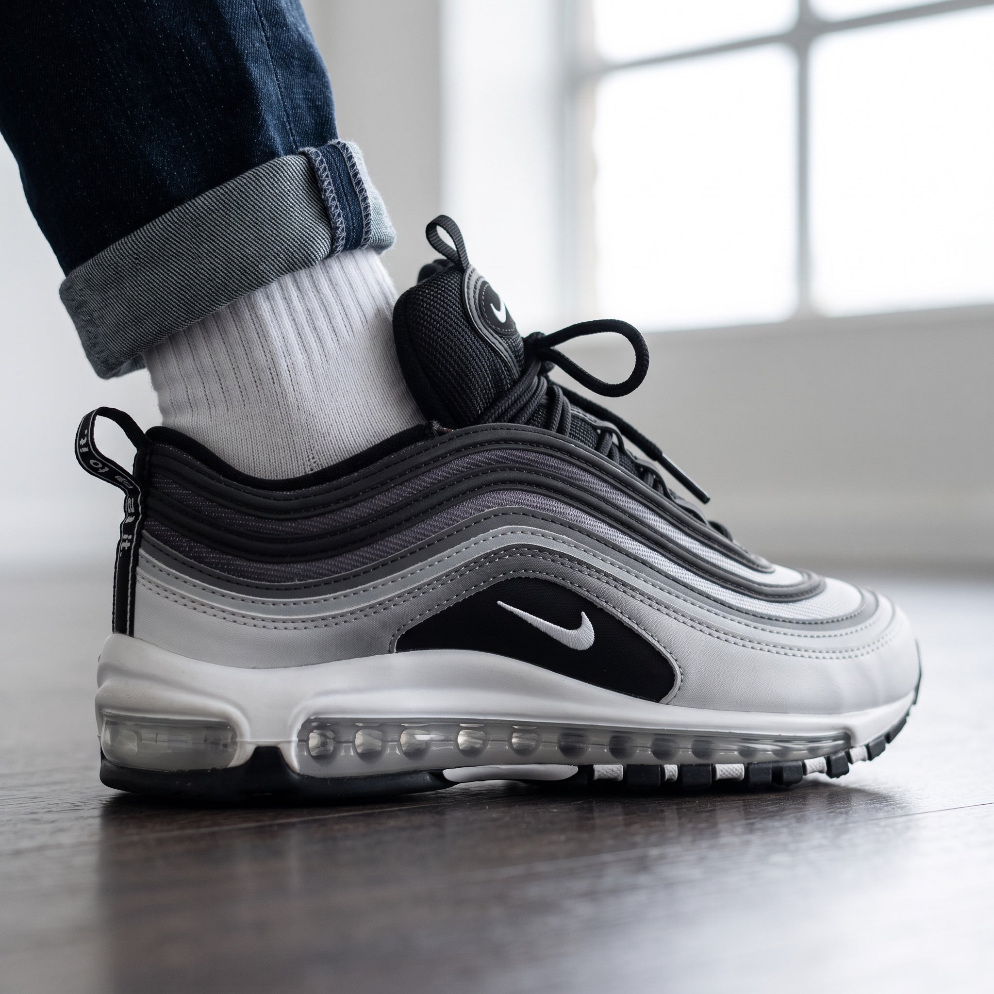 Nike Air Max 97 sneaker in silver, black and white showing wavy upper and full-length Air unit