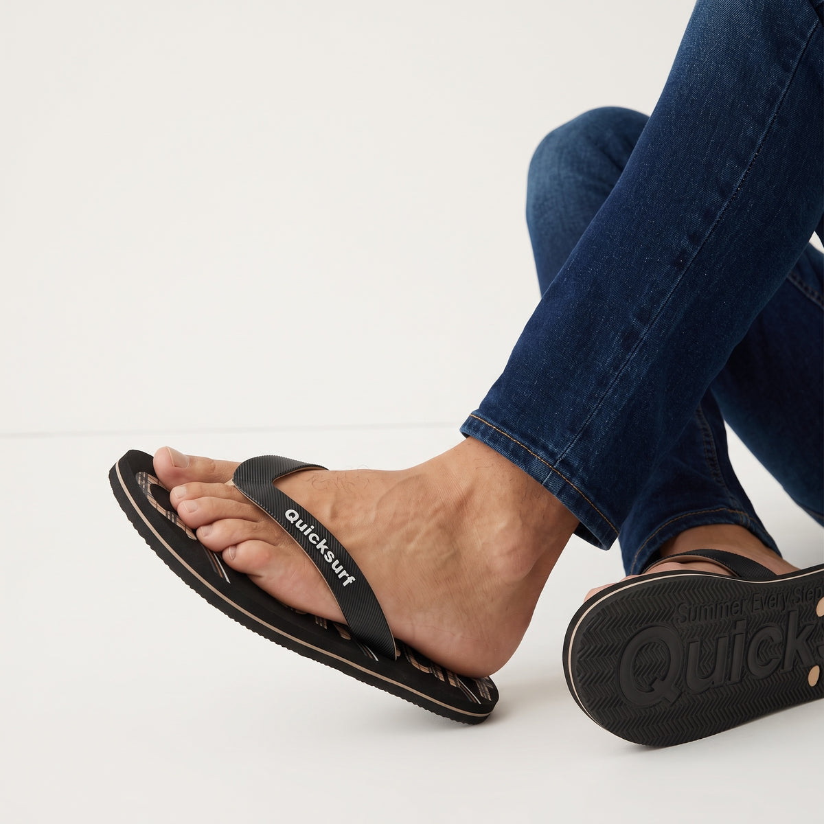 black Quicksurf flip flops with beige plaid printed footbed