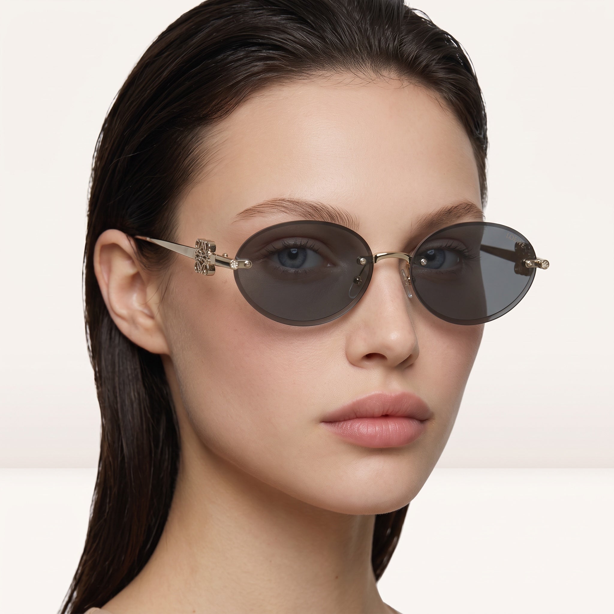 Round Loewe sunglasses with gold frame and brown lenses featuring decorative metal hinge