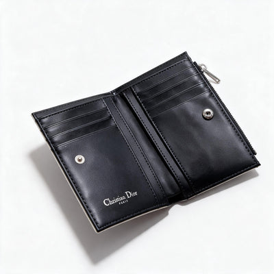 White quilted Dior compact wallet with black bow charm and black interior card slots