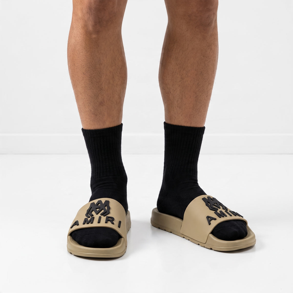 AMIRI beige rubber slides with black logo on model feet