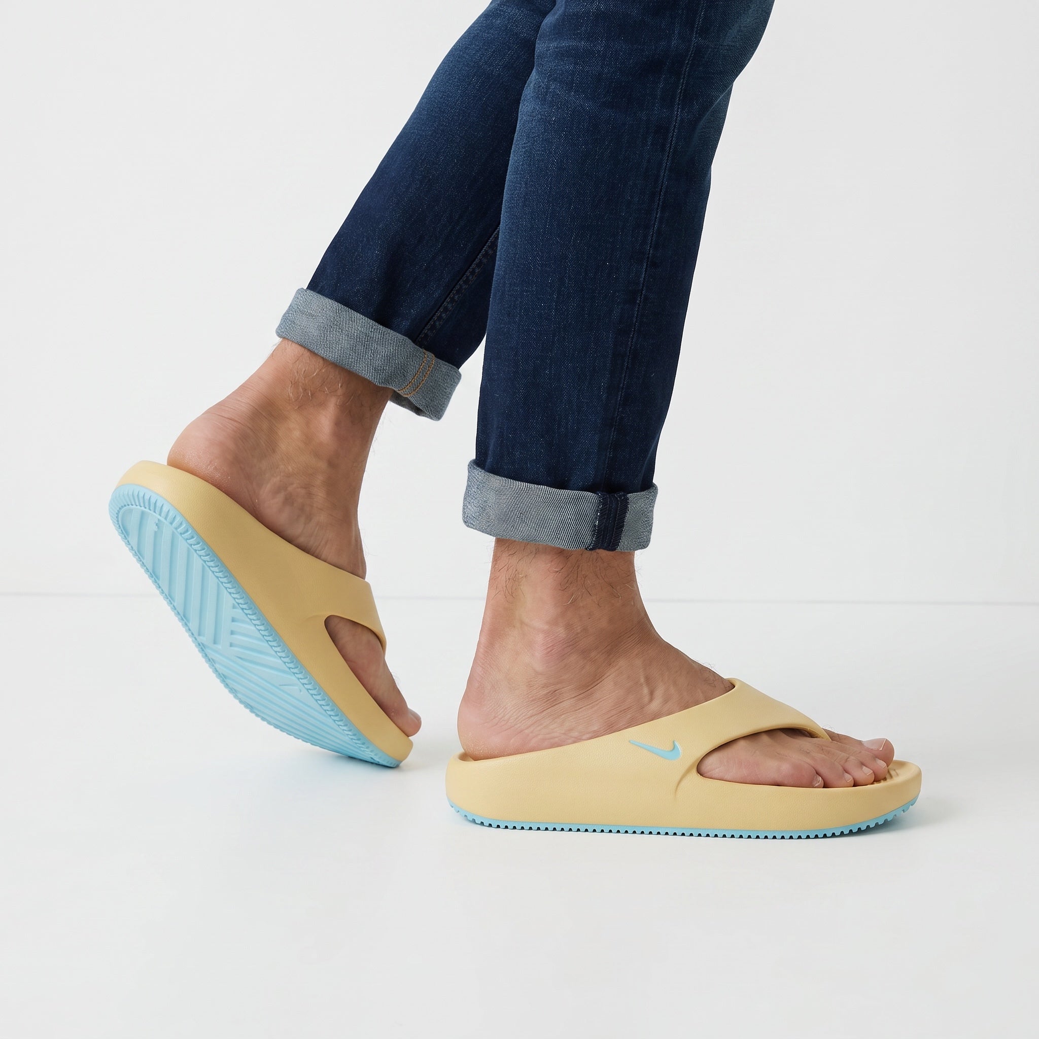 Nike pale yellow slides with aqua sole on model feet