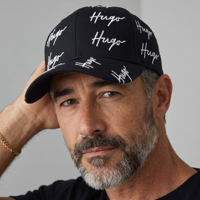 Black HUGO baseball cap with repeated white signature logo print
