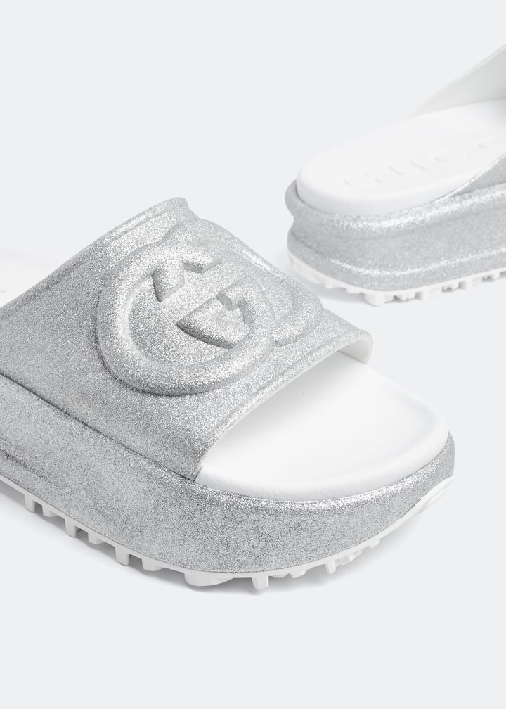 Silver Gucci flatform slides with glitter finish and raised interlocking G logo on white footbed