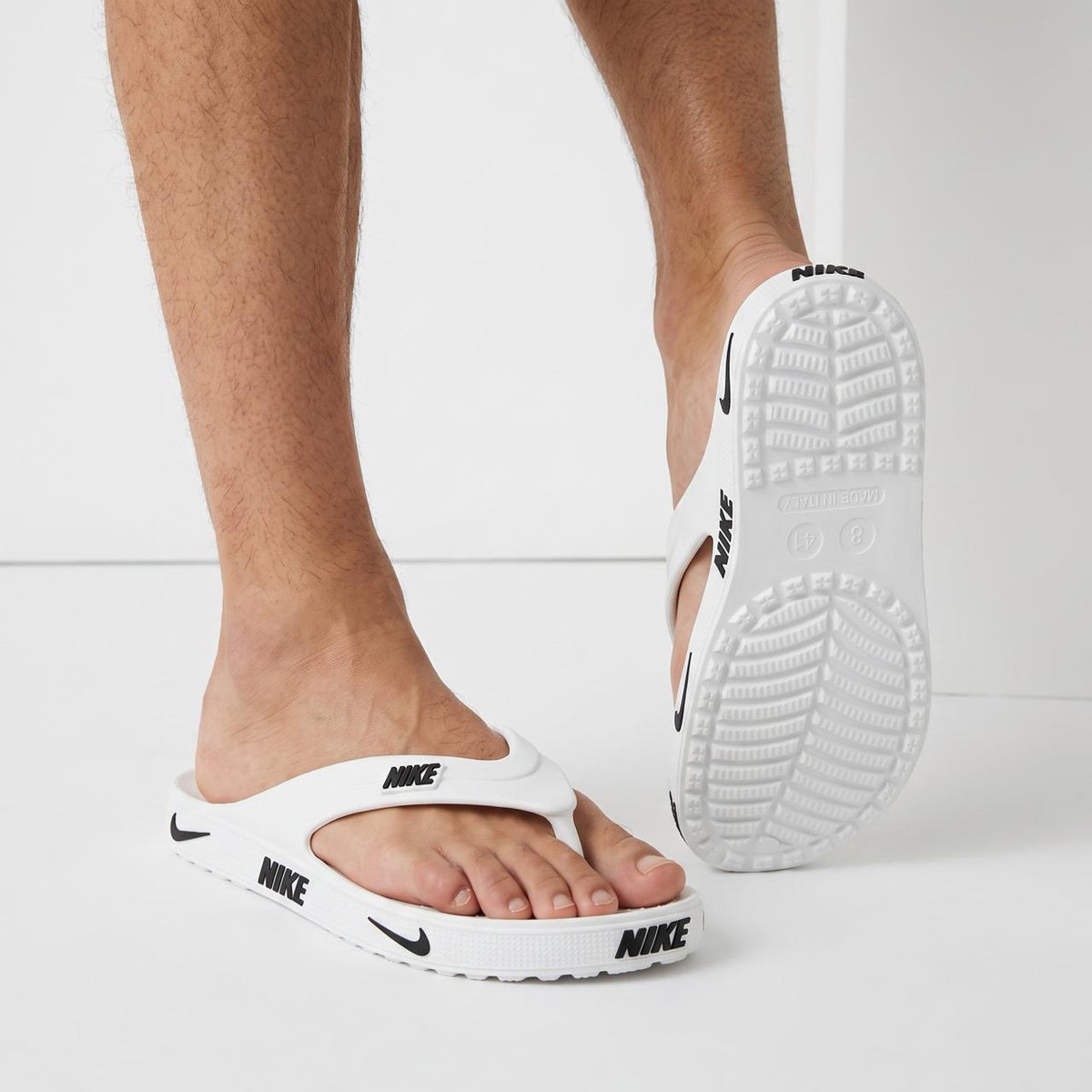 White Nike flip-flop sandals with black NIKE logos on strap and sole