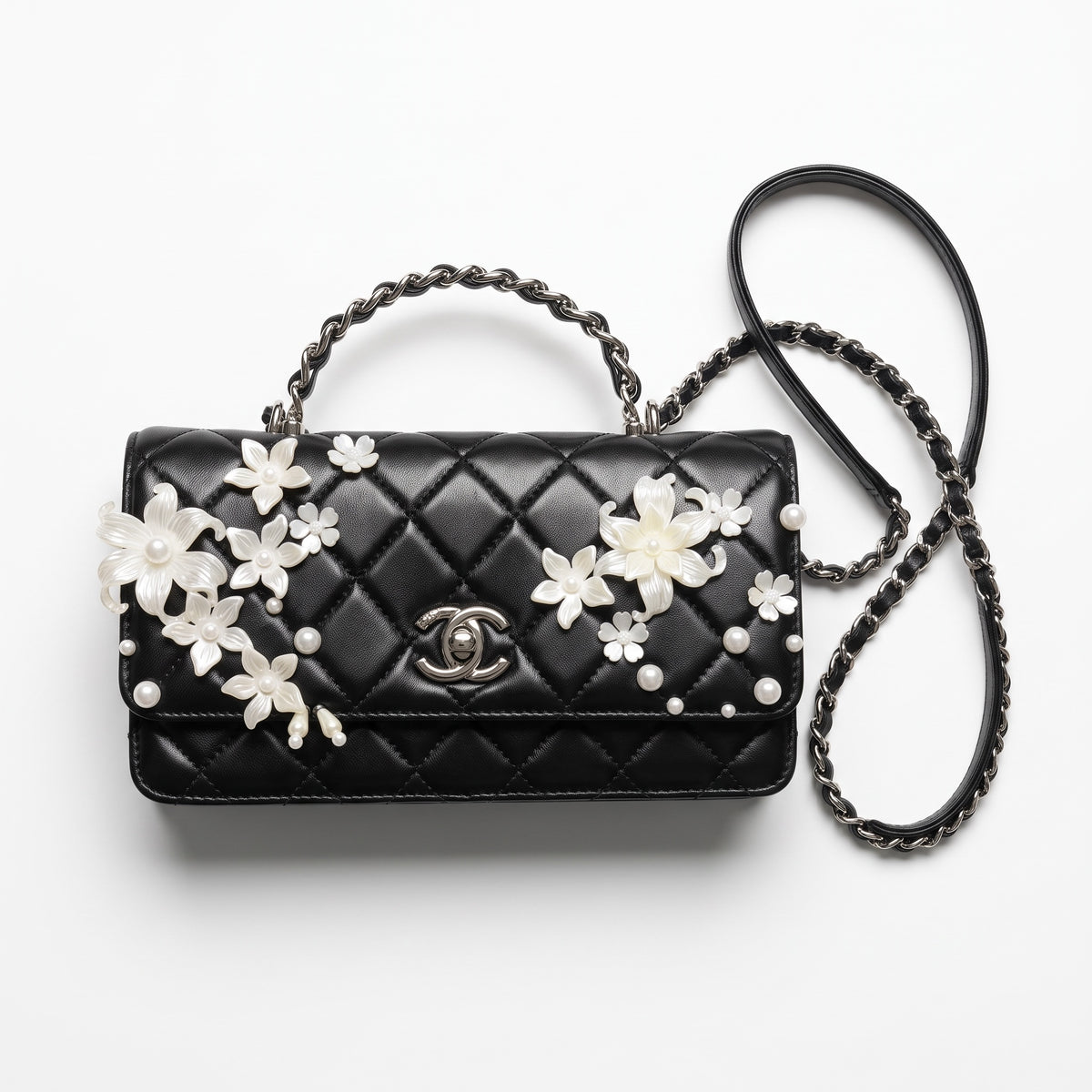 Black quilted Chanel top-handle bag with white floral pearl appliqués and chain strap