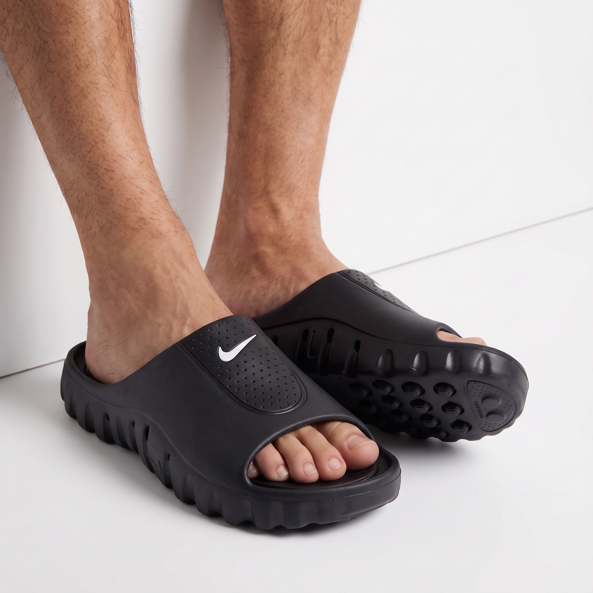 black Nike slip-on slide with white swoosh and sculpted sole