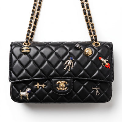 Black quilted Chanel flap bag with gold chain strap and decorative pins