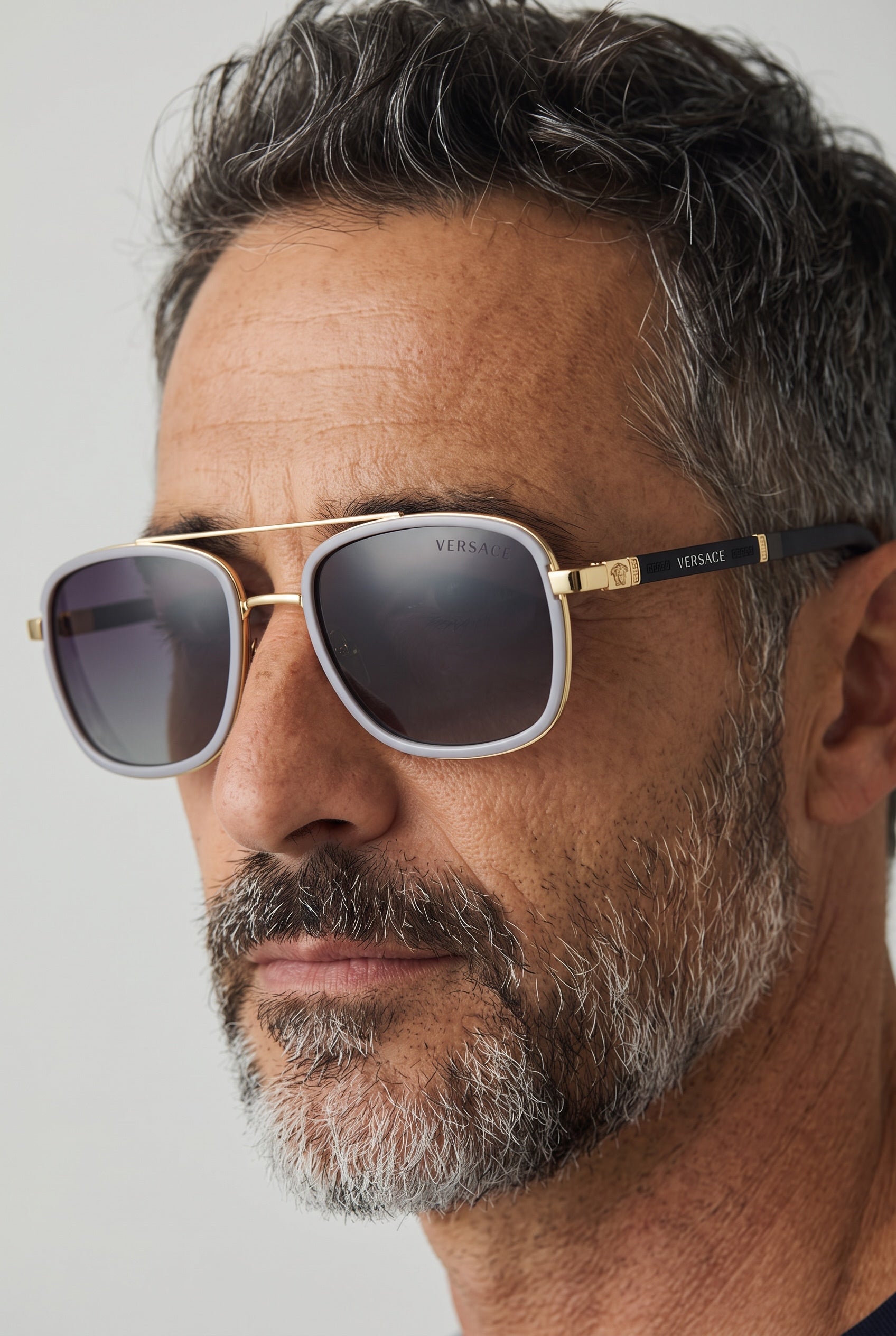 Versace gold metal sunglasses with white rim and grey lenses on a man