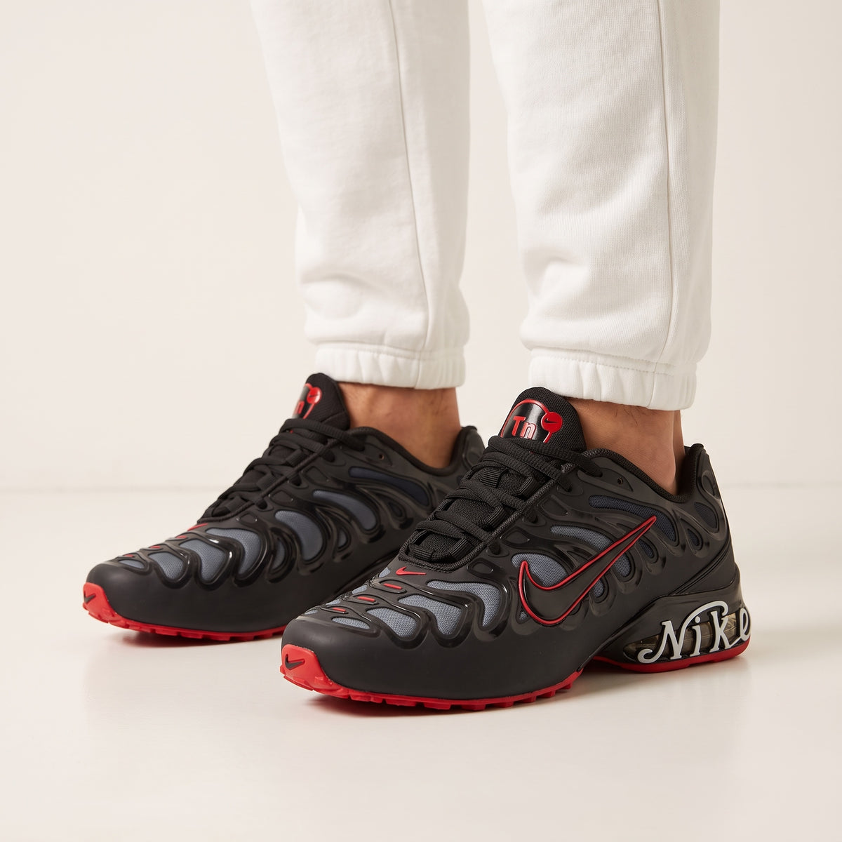 Black Nike Tn-style sneakers with red accents and wave overlays