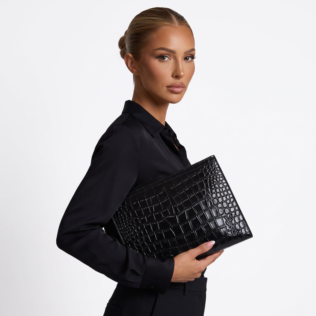 Black croc-embossed Saint Laurent zip pouch with YSL logo held under arm